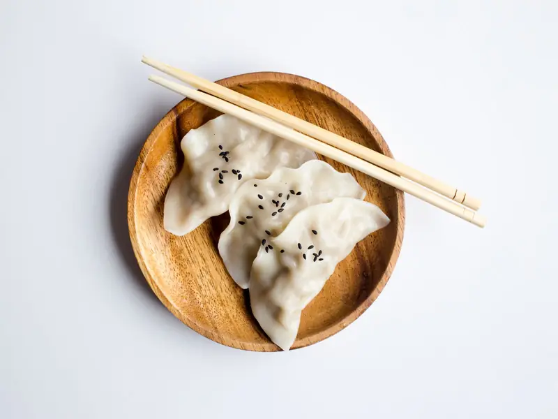Handmade dumplings in a wooden bowl with chopsticks