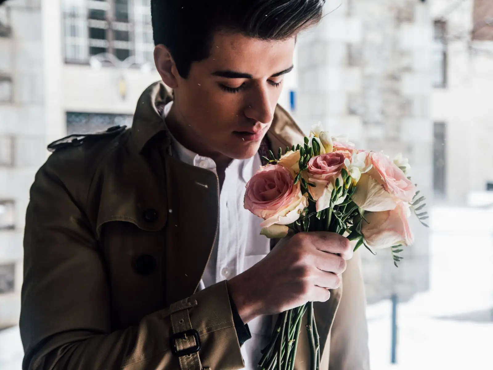 A man holding a hand-tied bouquet of pink roses