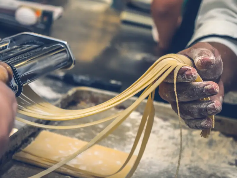 Fresh pasta ribbons coming out of a pasta machine
