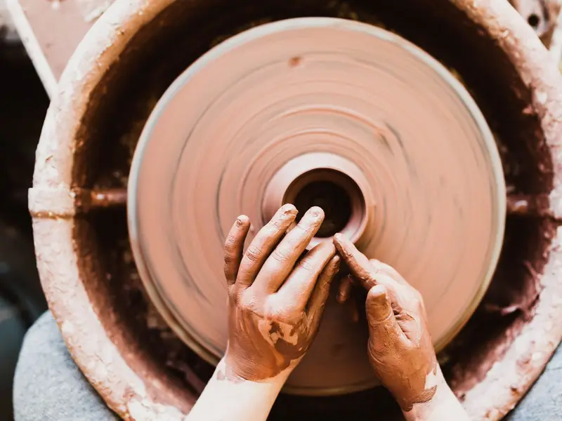 Hands shaping clay on a spinning potter's wheel